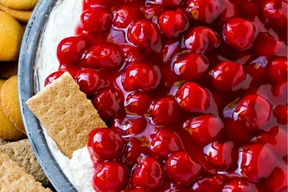 A bowl of cream cheese cherry cheesecake dip with crackers.