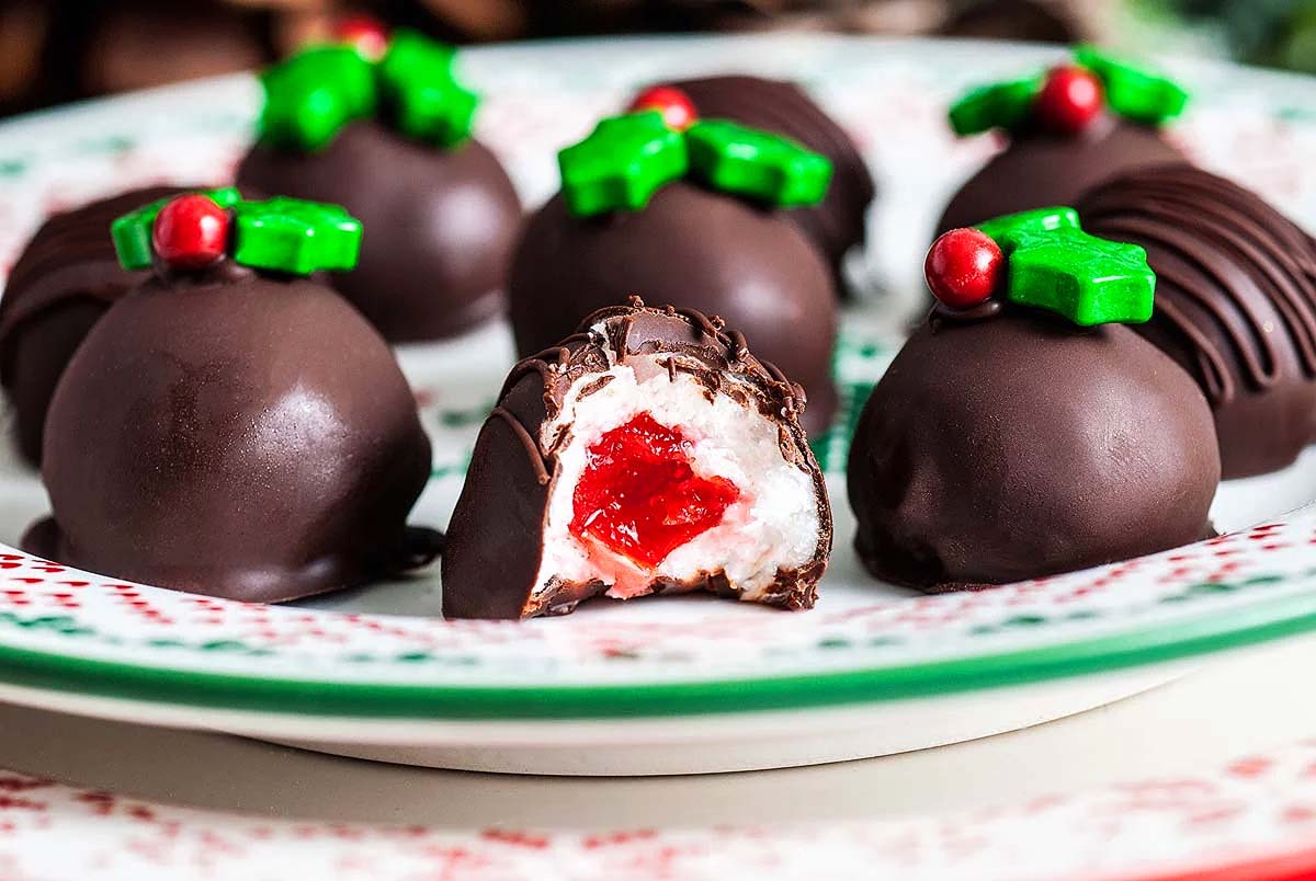 Christmas chocolate holly balls on a plate with holly leaves.