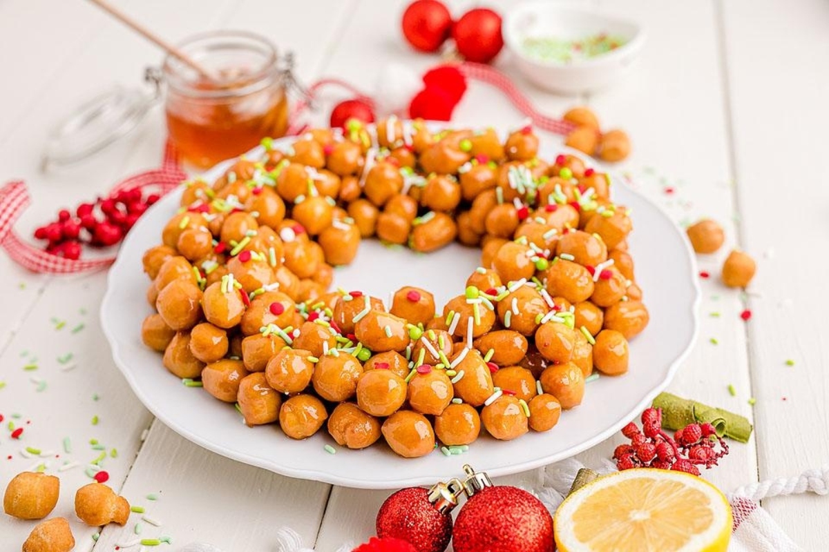 A plate with a wreath of nuts and lemons  on it, perfect for Christmas recipes.