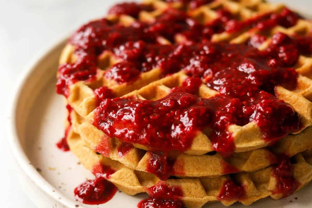 A mouthwatering stack of waffles drizzled with delicious raspberry sauce.