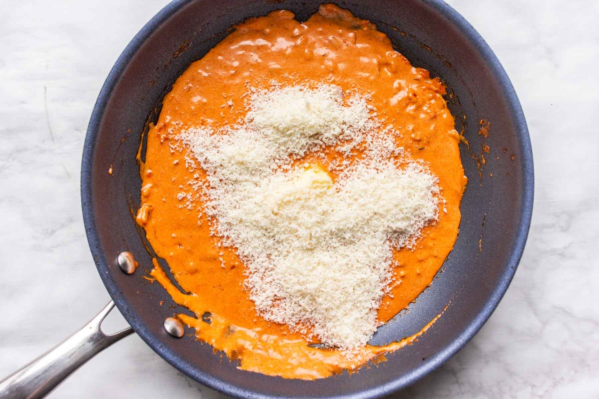 A quick and easy recipe featuring a frying pan filled with tomato sauce and parmesan cheese, perfect for pasta enthusiasts.