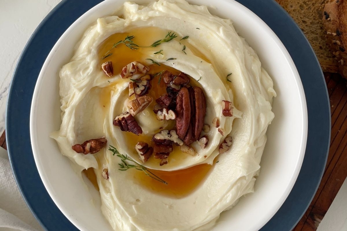 A creamy bowl of hummus with pecans and bread.