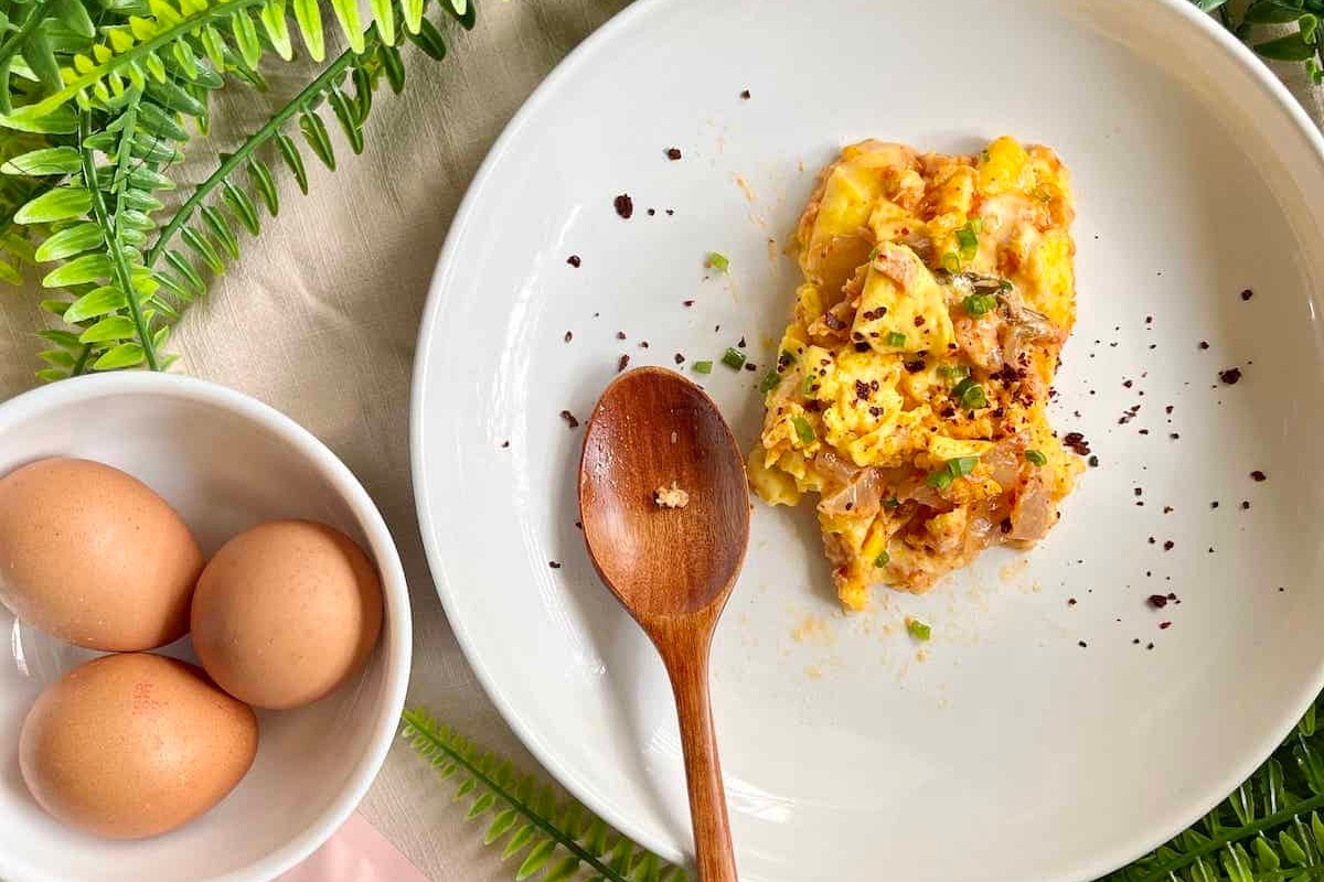 A healthy breakfast with high protein featuring a plate of eggs and a wooden spoon.