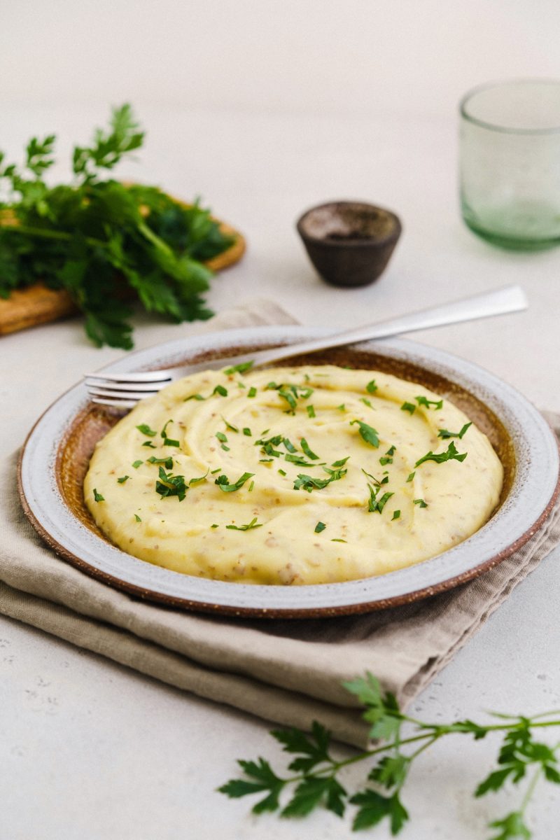 Red skin mashed potatoes with parsley on a plate.