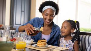 A mother and daughter enjoying freshly made pancakes at a breakfast table.