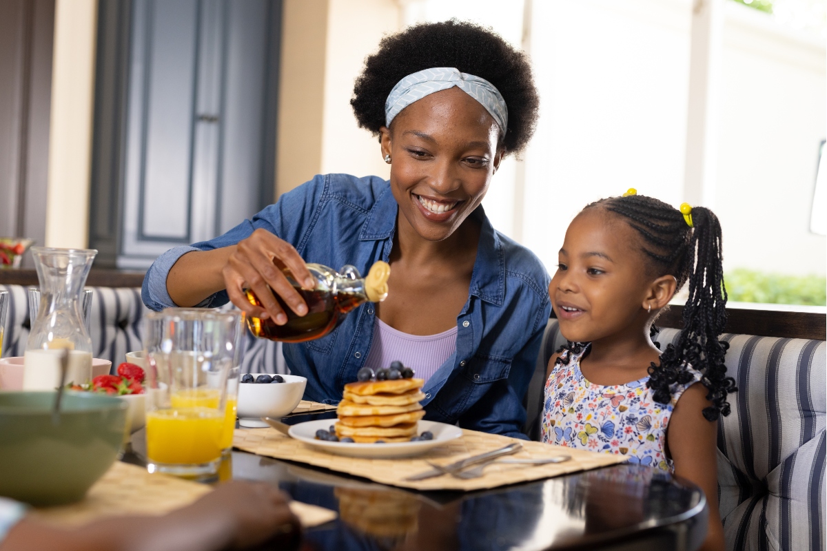 A mother and daughter savoring breakfast at a restaurant, while discussing how to reheat pancakes.