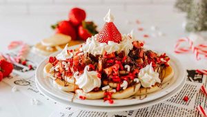 An easy and festive plate of pancakes topped with whipped cream and strawberries, perfect for a delicious Christmas breakfast.