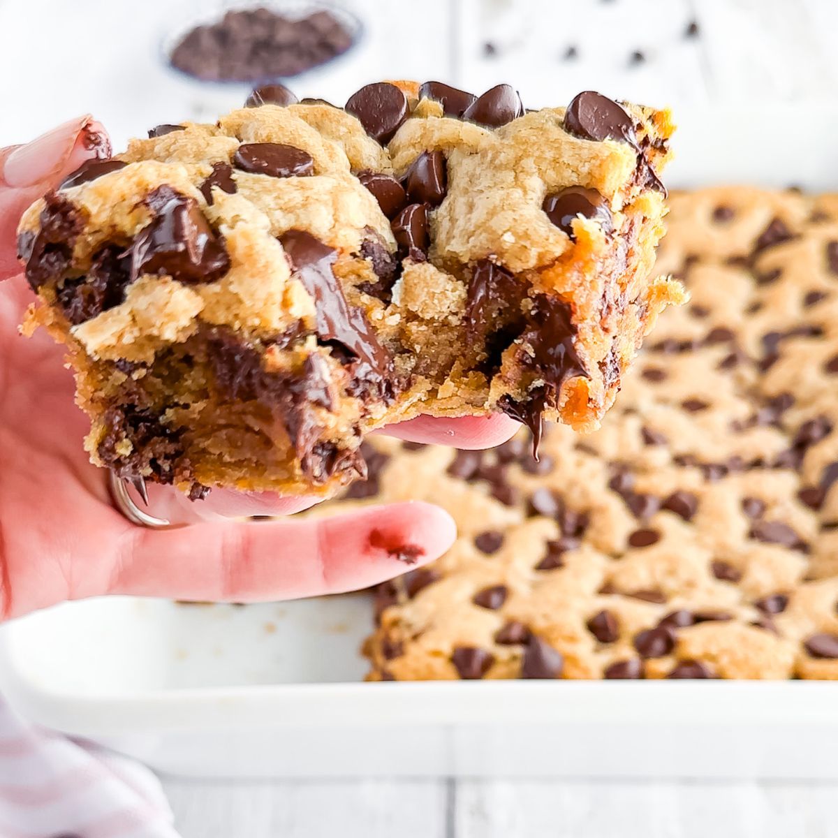 A hand holding a peanut butter chocolate chip cookie bar.