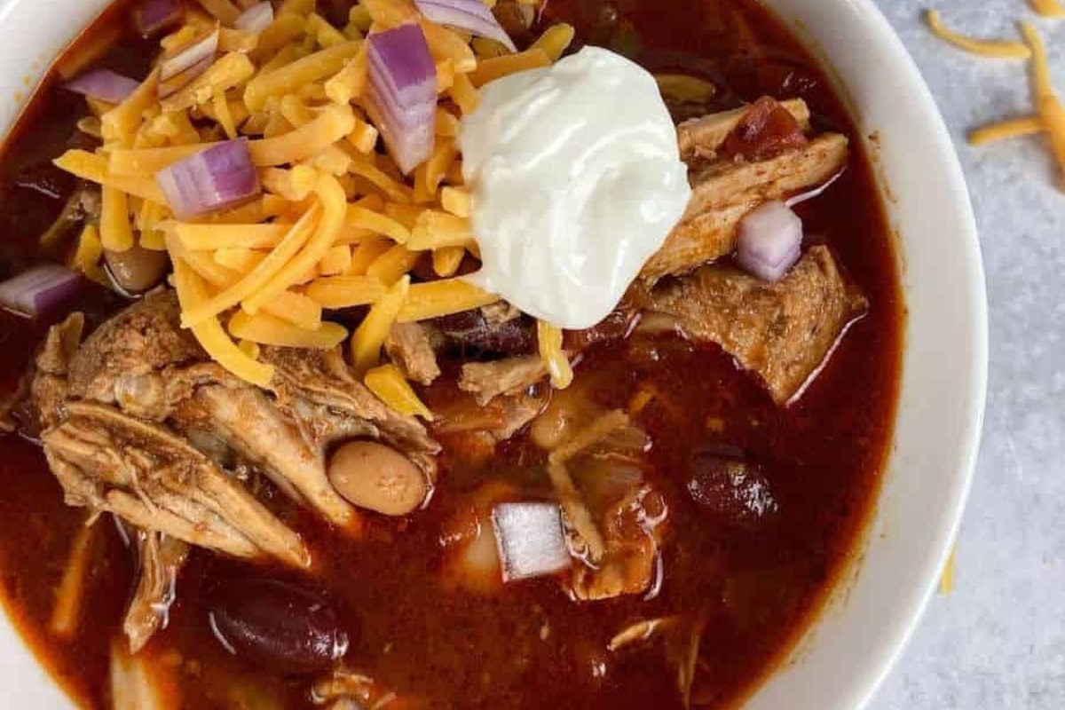 A flavorful bowl of slow cooker chicken chili topped with cheese and sour cream.