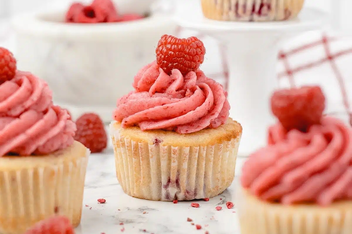 Indulge in these delectable Raspberry cupcakes, perfect for a romantic Valentines' day dessert. Each cupcake is crowned with a fluffy swirl of whipped cream and adorned with fresh raspberries,