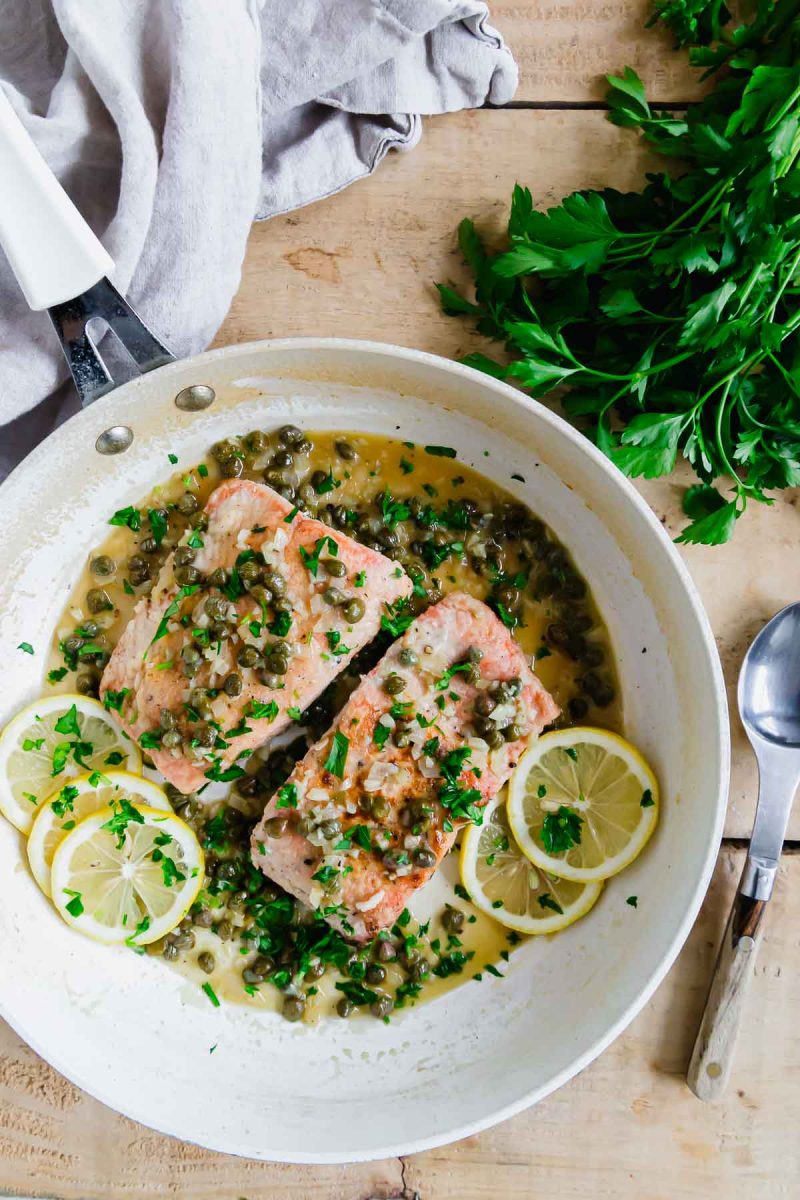Salmon piccata with lemon and parsley in a skillet.