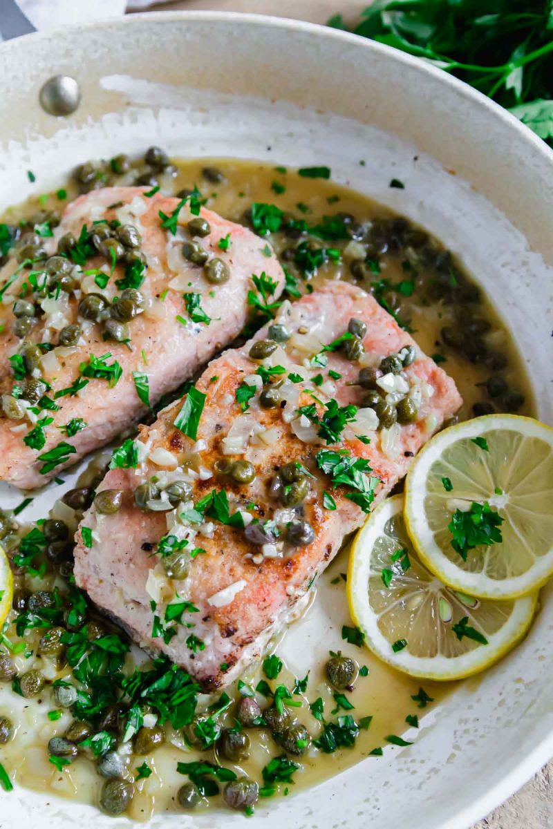 Salmon piccata with lemon and capers in a skillet.