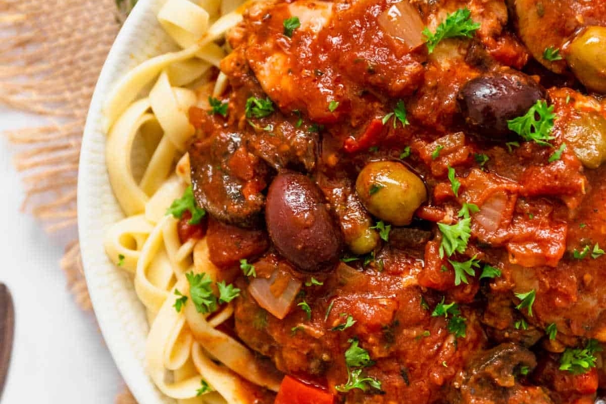 A bowl of pasta with meat sauce and olives.