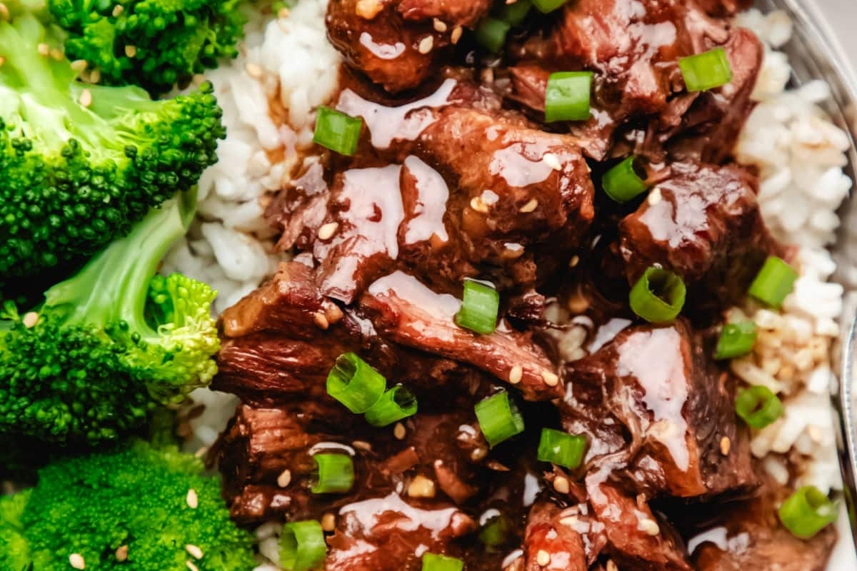 A bowl of asian beef and broccoli with a fork.