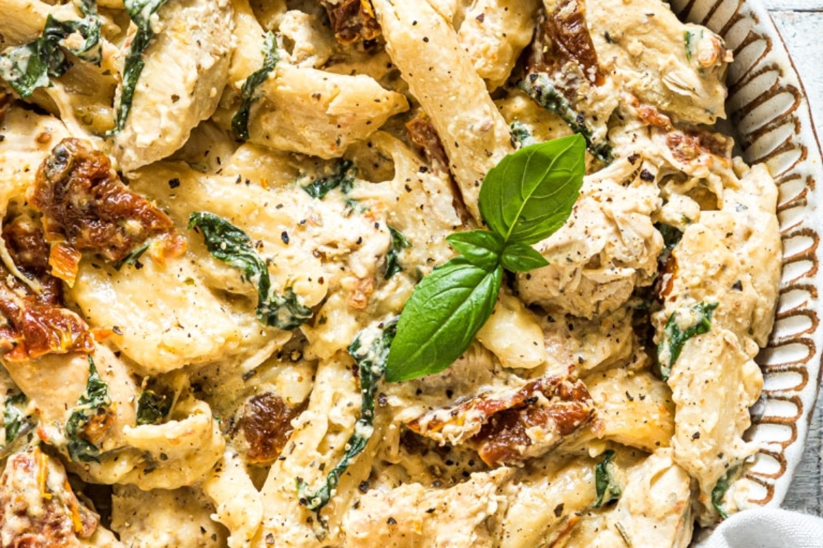 Chicken and spinach pasta in a white bowl.