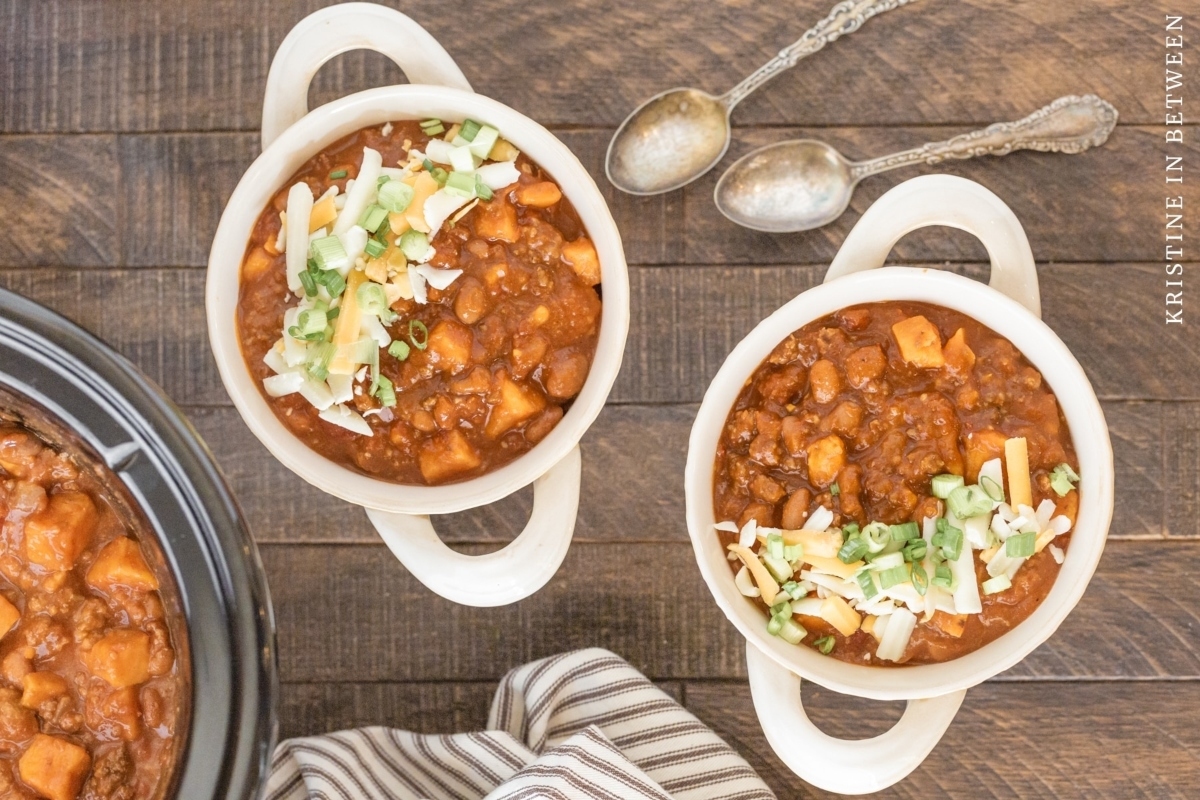 Three bowls of chili cooked in a slow cooker, placed on a wooden table.