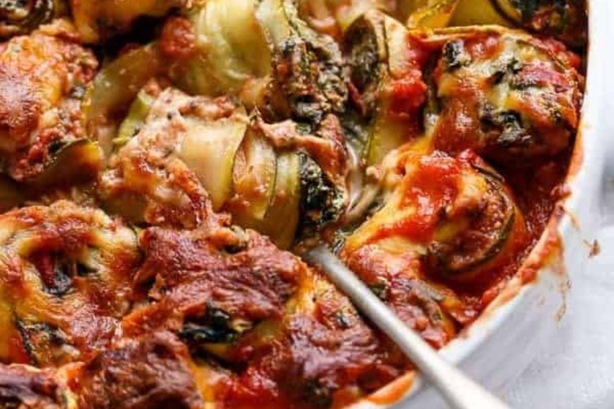 A spinach casserole dish with meat and vegetables in it.