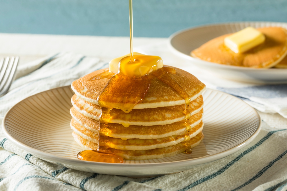 A stack of pancakes is being drizzled with syrup and suggestions on how to reheat pancakes.