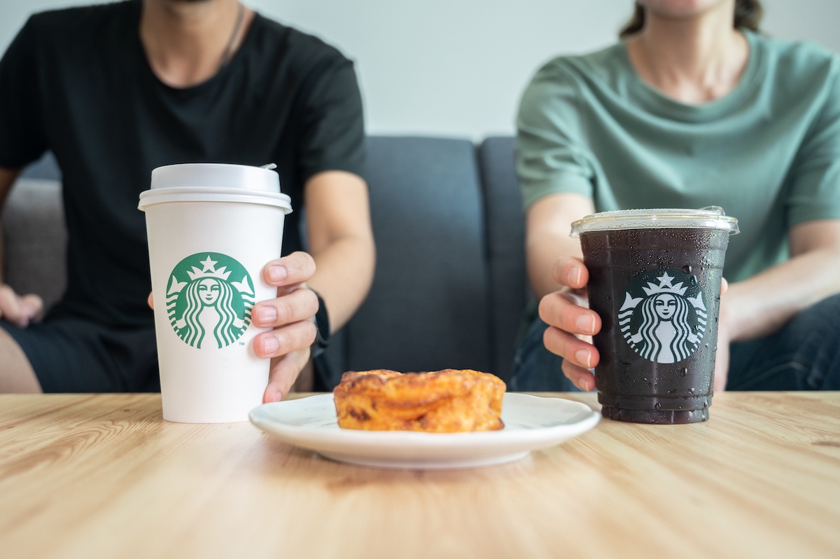 Two people enjoying Starbucks coffee and a donut from the breakfast menu.