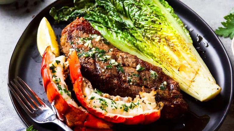 Surf and turf, a mouthwatering combination of steak and lobster, beautifully presented on a black plate.