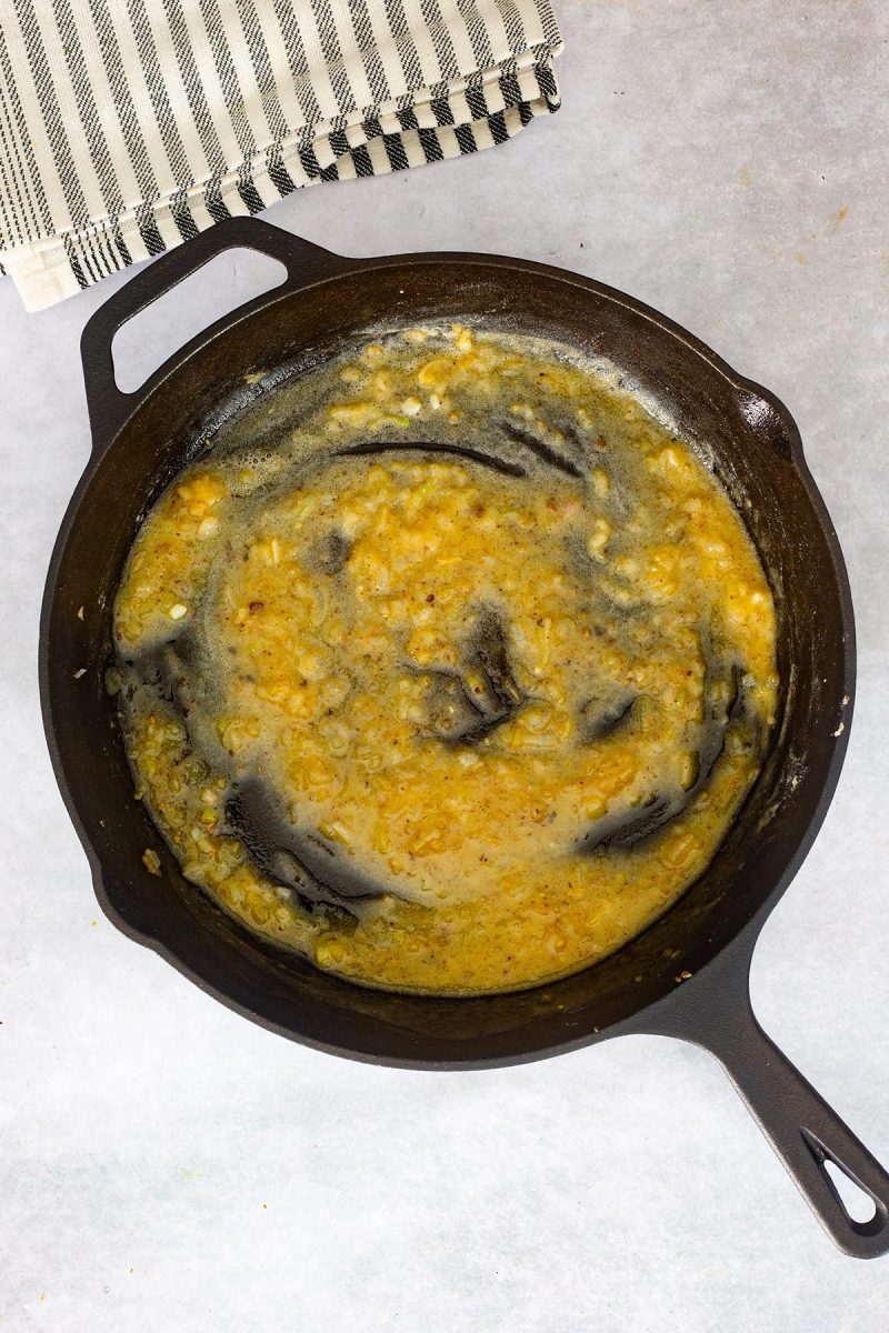 A cast iron skillet filled with loaded mashed potatoes.