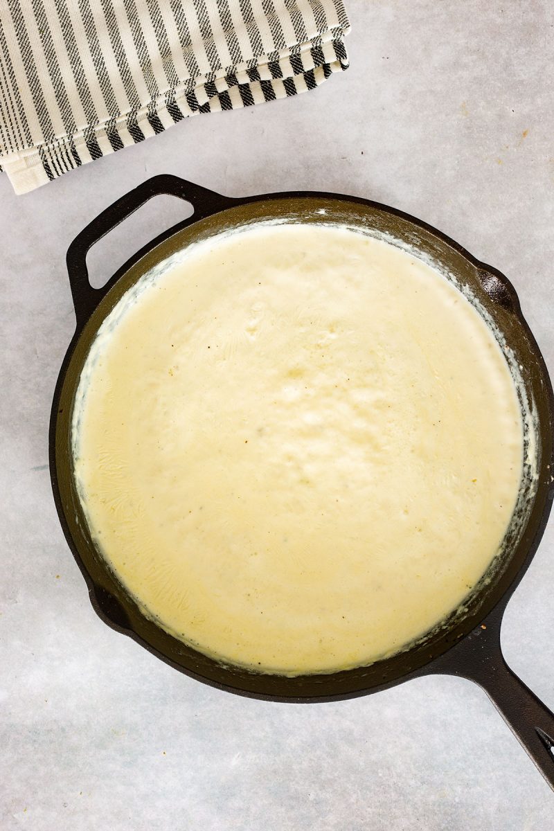 A cast iron skillet filled with loaded mac and cheese in a creamy sauce.