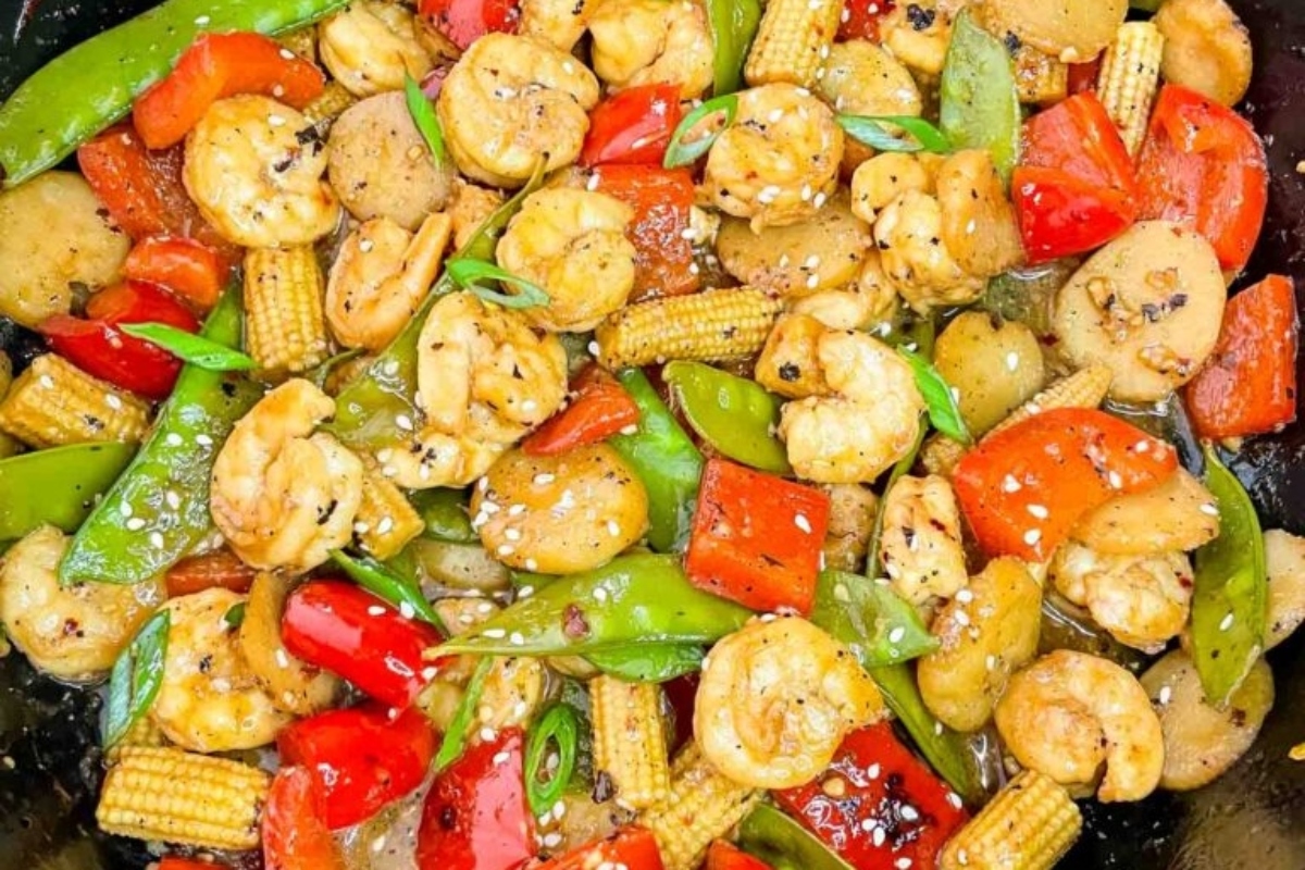 Shrimp stir fry in a skillet with peppers and corn, perfect for shrimp dinners.