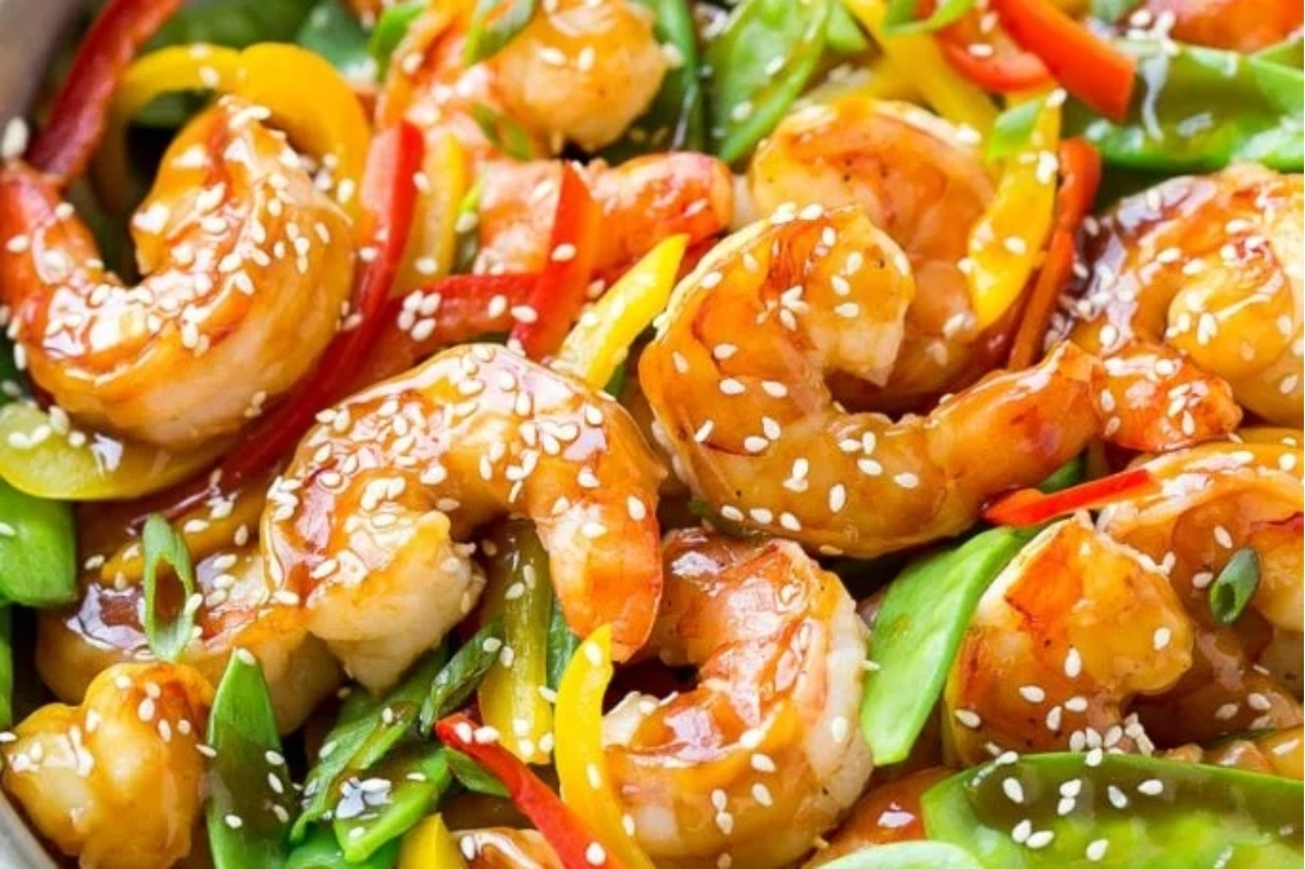 A close up of shrimp and vegetables sizzling in a skillet.