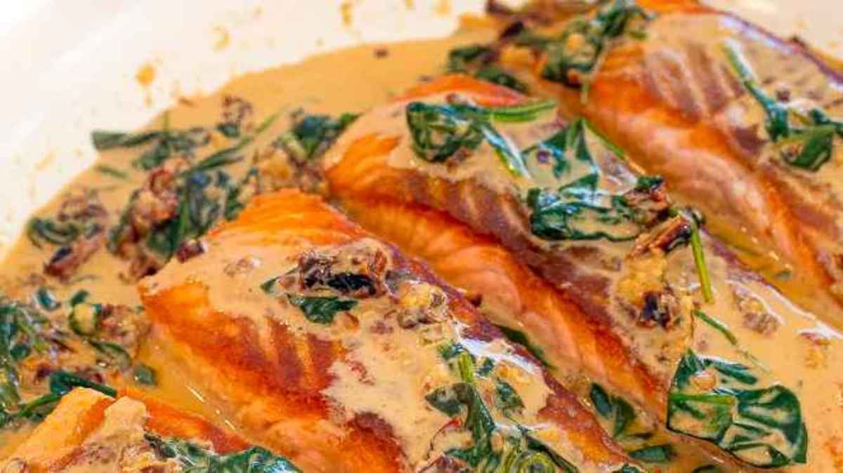 Valentine's Day Salmon Fillets: Enjoy a romantic main dish of salmon fillets served with a delectable sauce and accompanied by vibrant spinach, all beautifully presented in a white dish.