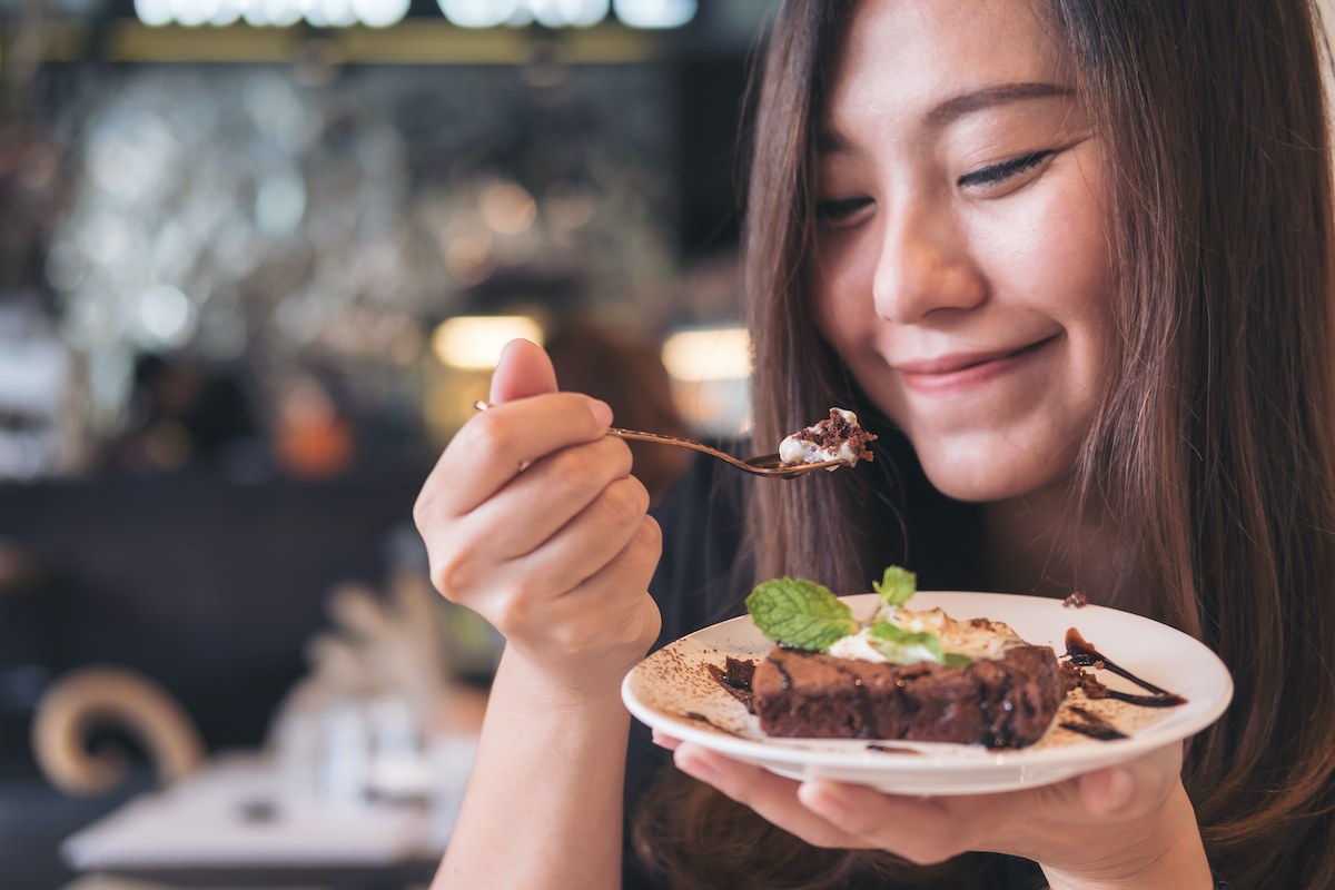 A woman indulging in a delicious chocolate brownie in a restaurant.