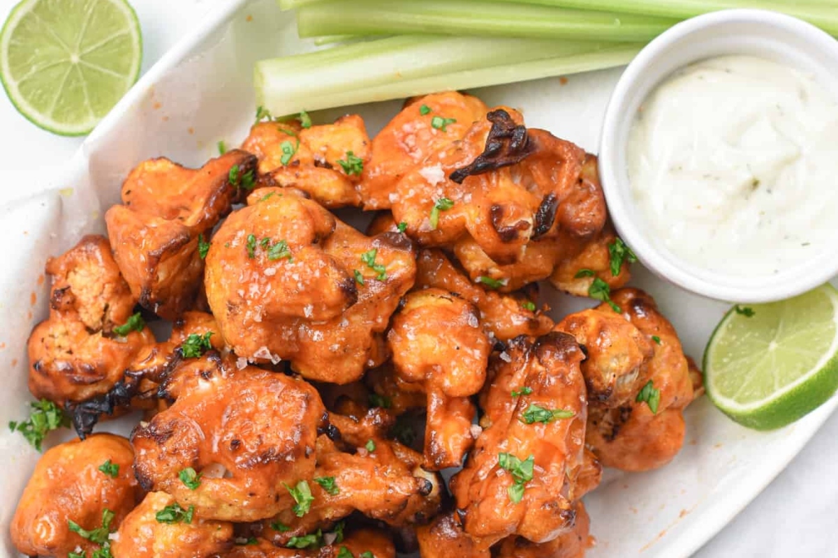 31 Guilt-Free Air Fryer Recipes for Every Meal 21 Buffalo chicken wings on a white plate with limes and celery.