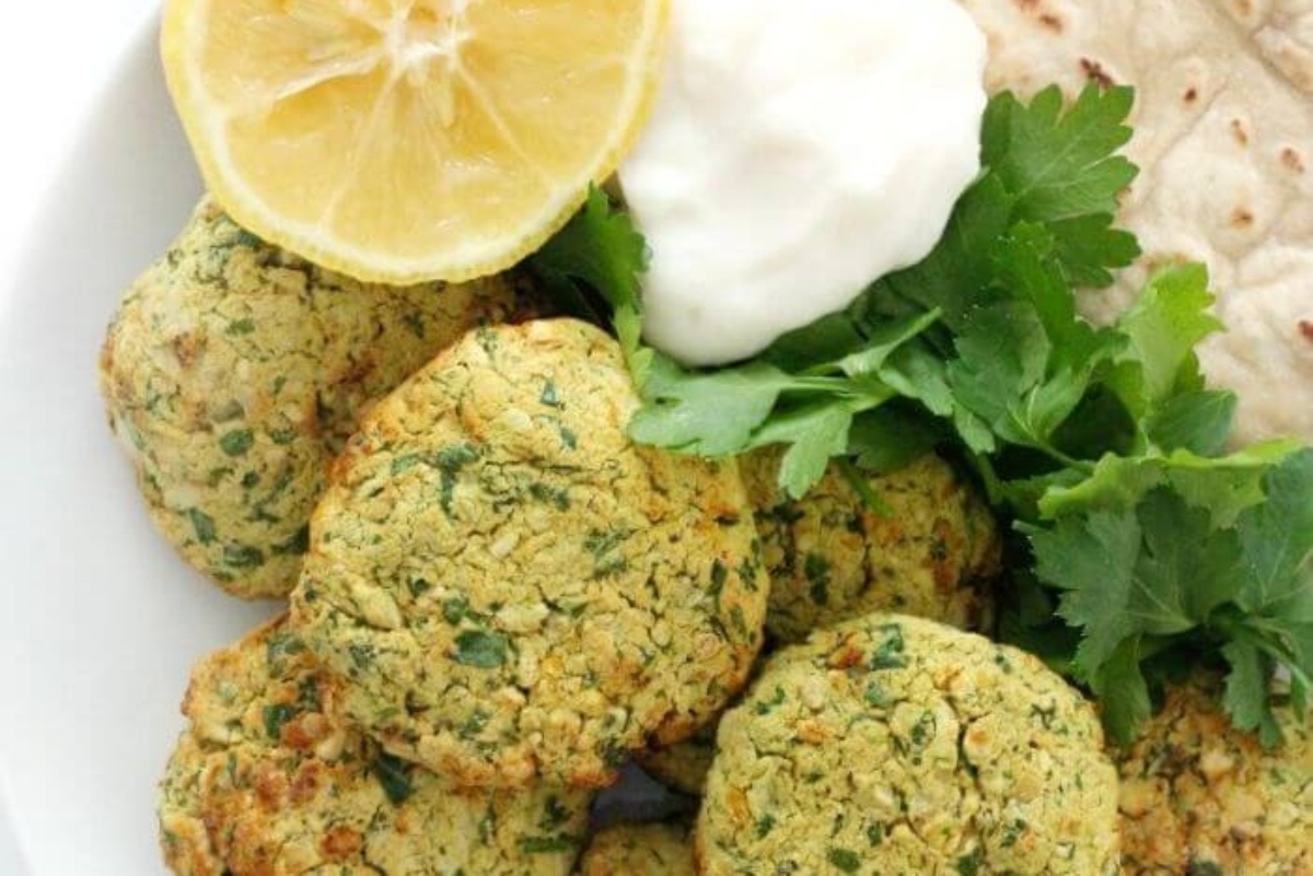 A plate of falafel with tzatziki sauce and pita bread.