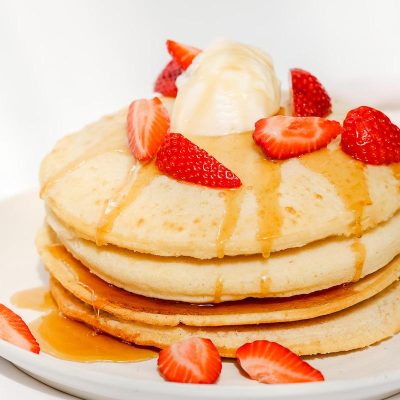 Air fryer pancakes topped with strawberries and syrup.