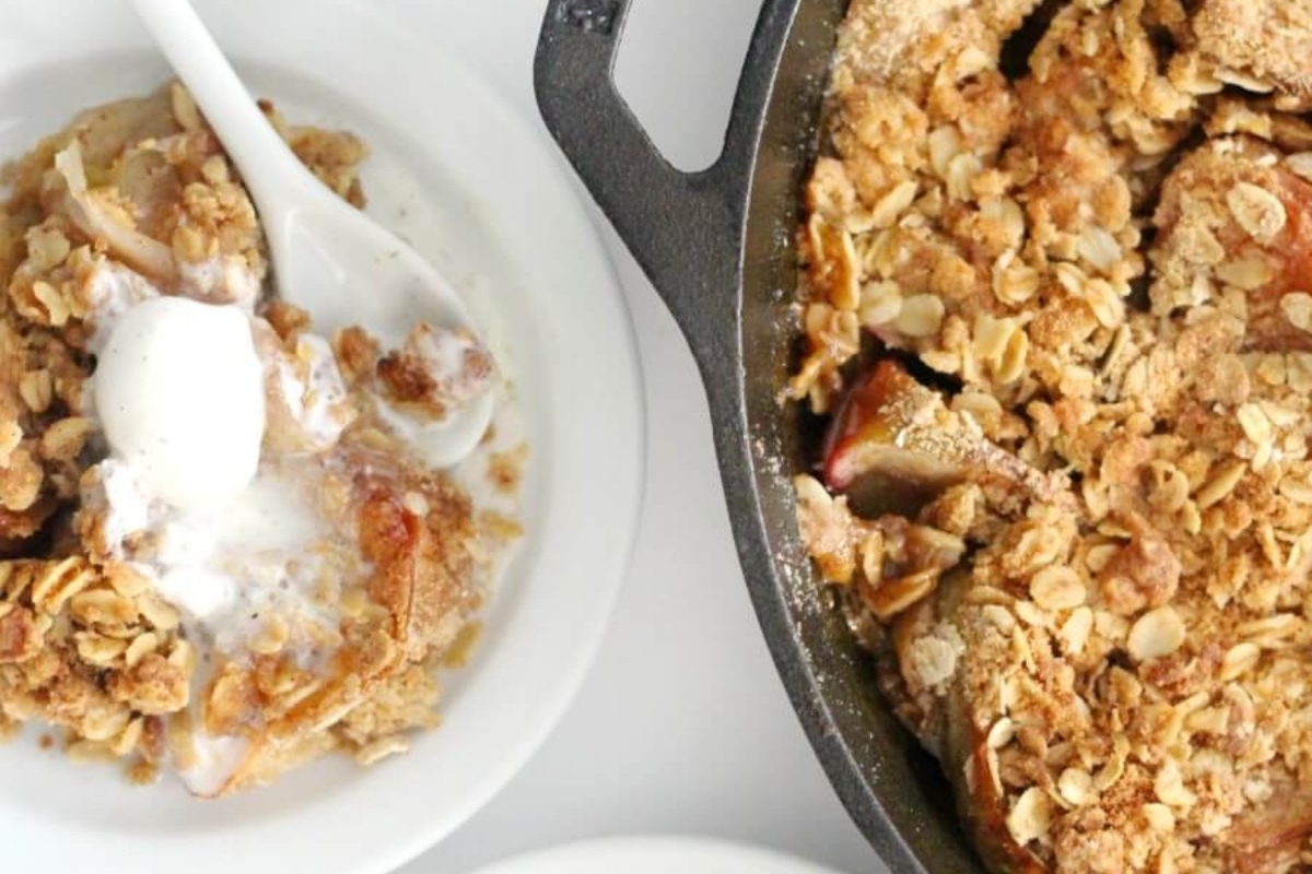 Apple crisp in a skillet with ice cream and granola.