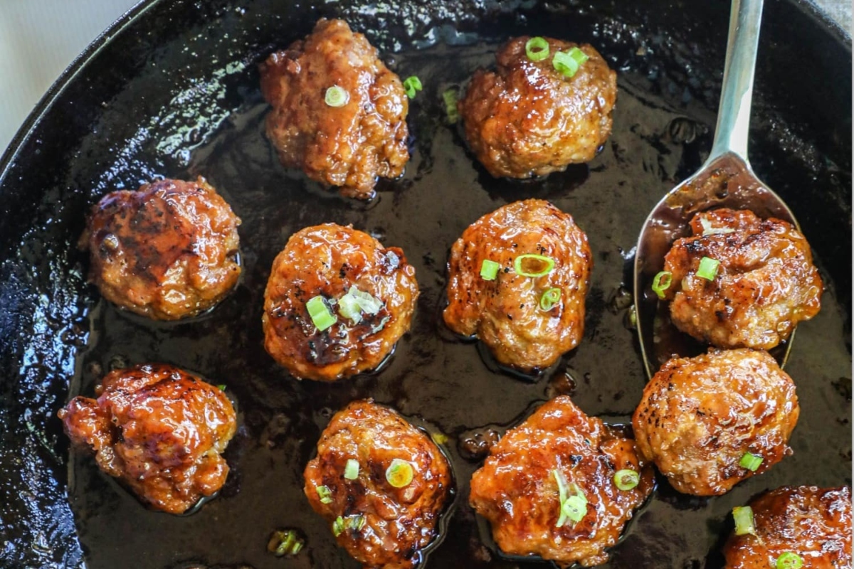 Meatballs in a skillet with green onions.