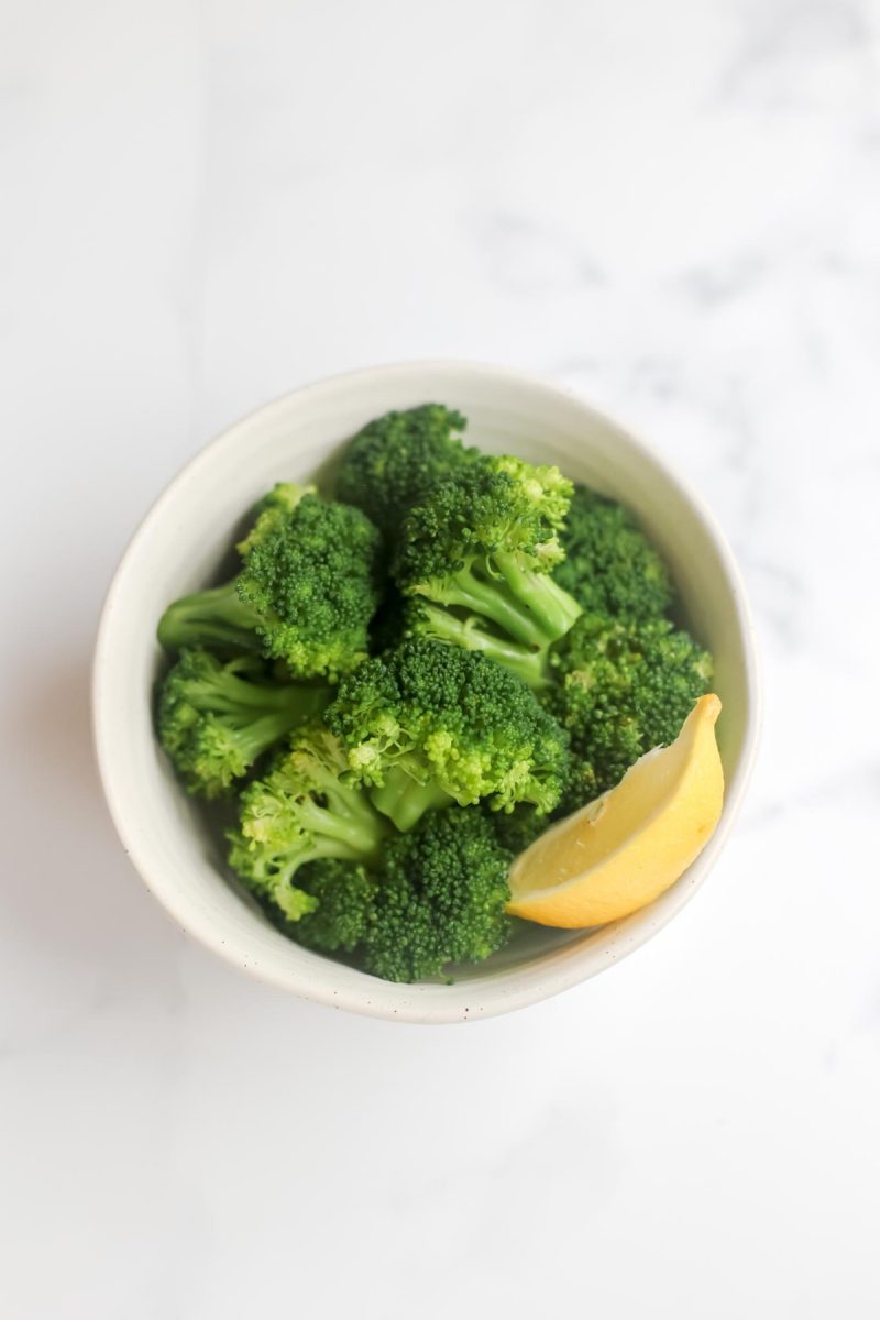 A bowl of broccoli with a slice of lemon.