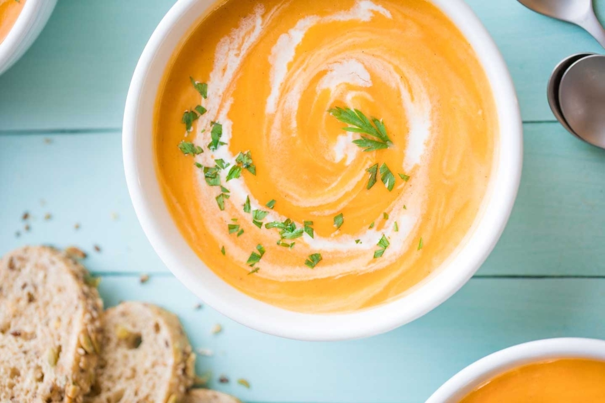 Creative Sweet Potato Recipes 16 Three bowls of carrot soup on a wooden table.