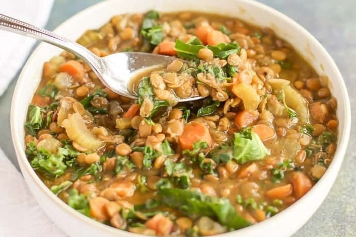 A bowl of lentil and kale soup with a spoon.