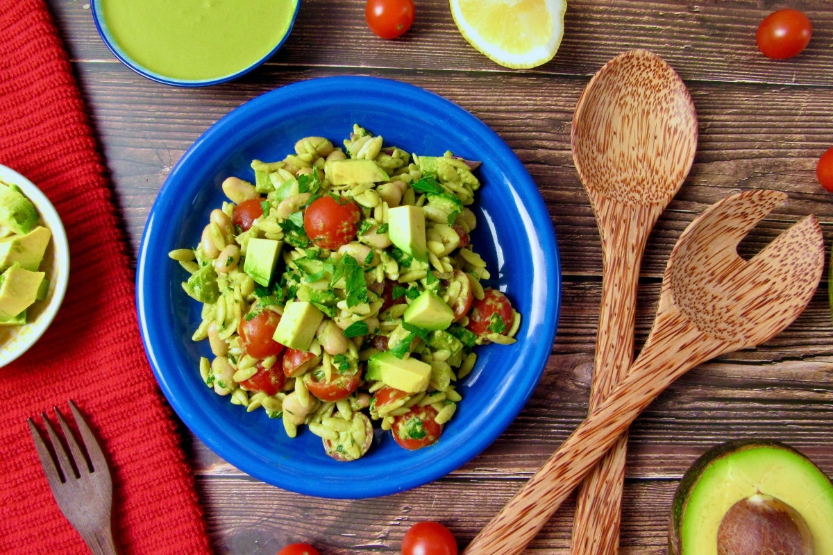 A bowl of guacamole, tomatoes and avocados on a wooden table.