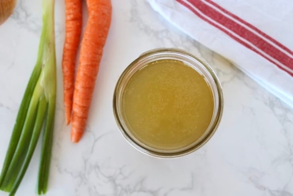 A jar of honey mustard with carrots and onions.
