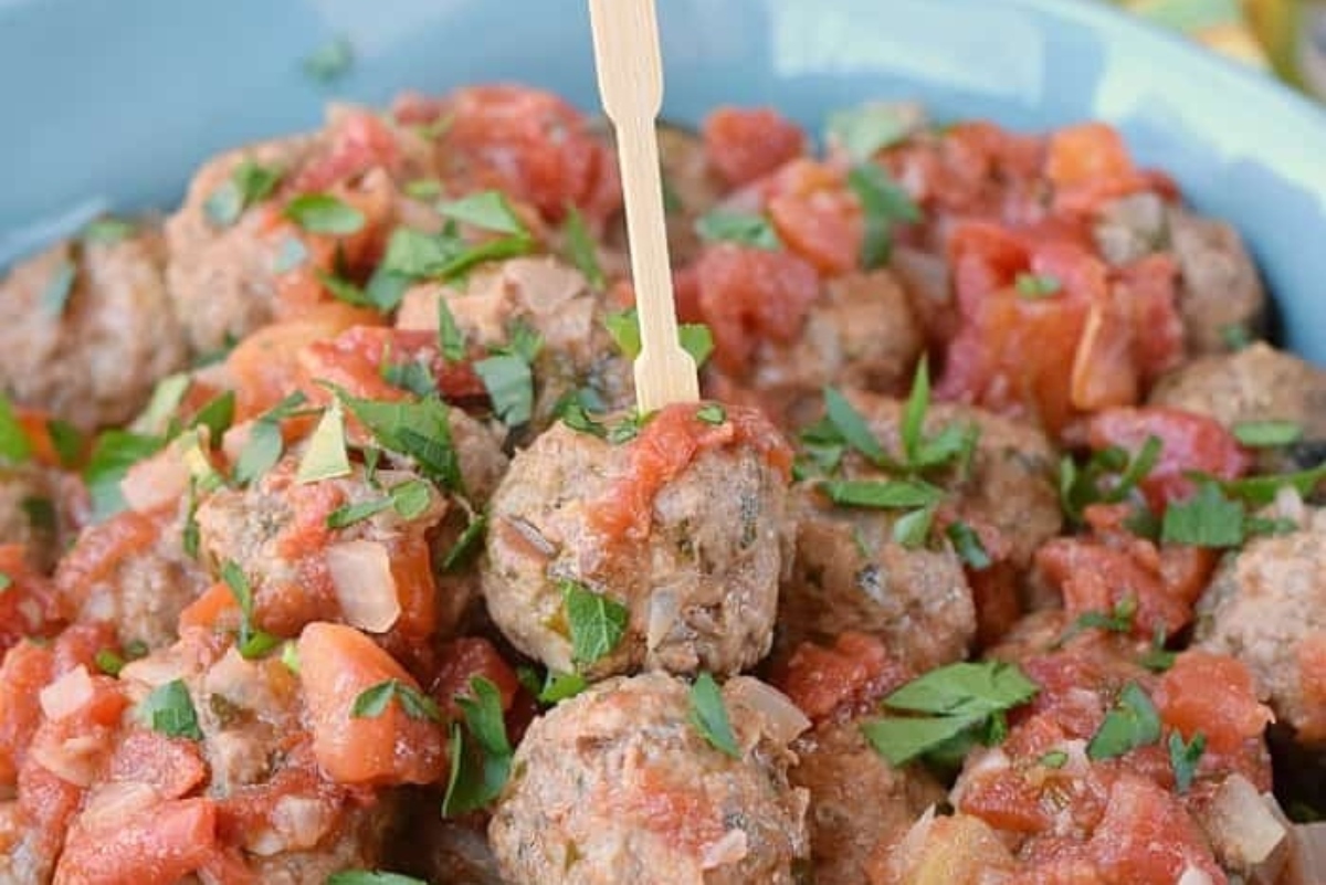Meatballs in tomato sauce with a wooden spoon.
