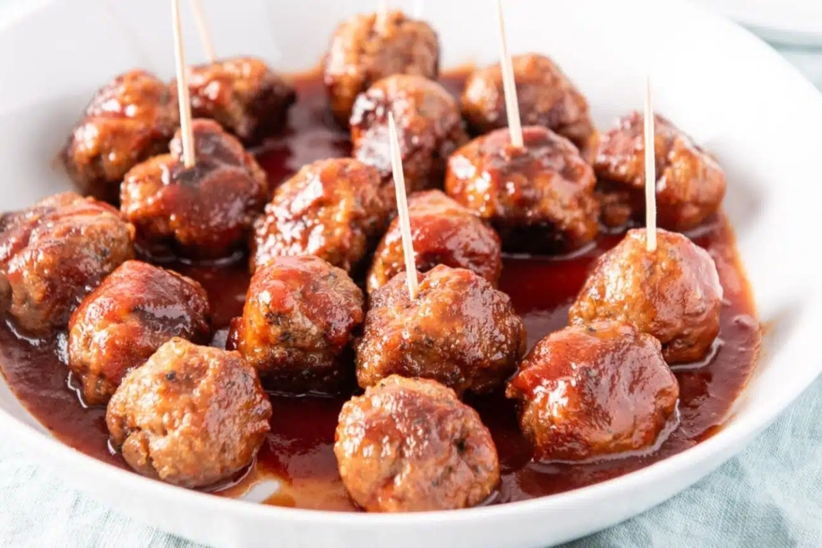 Meatballs in a white bowl with toothpicks.