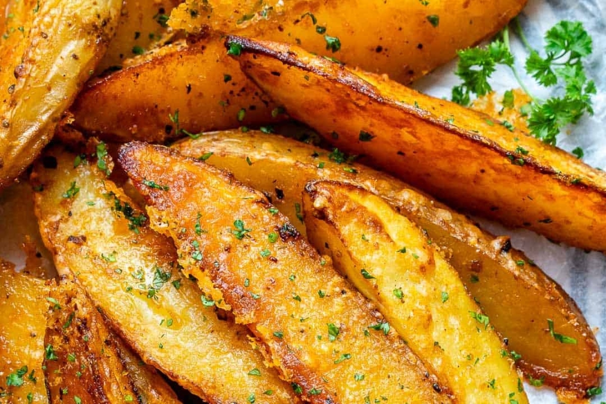 A plate of fried potato wedges with parsley.