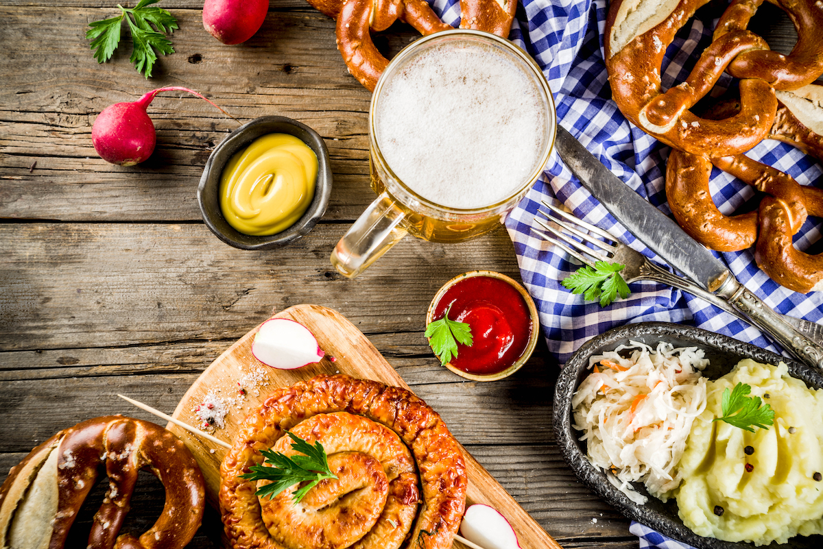 Oktoberfest food menu, bavarian sausages with pretzels, mashed potato, sauerkraut, beer bottle and mug old rustic wooden background