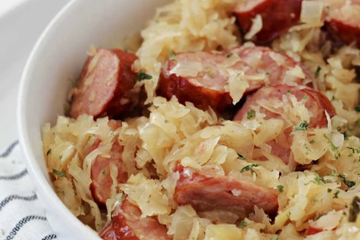 A bowl of sauerkraut and sausage in a white bowl.