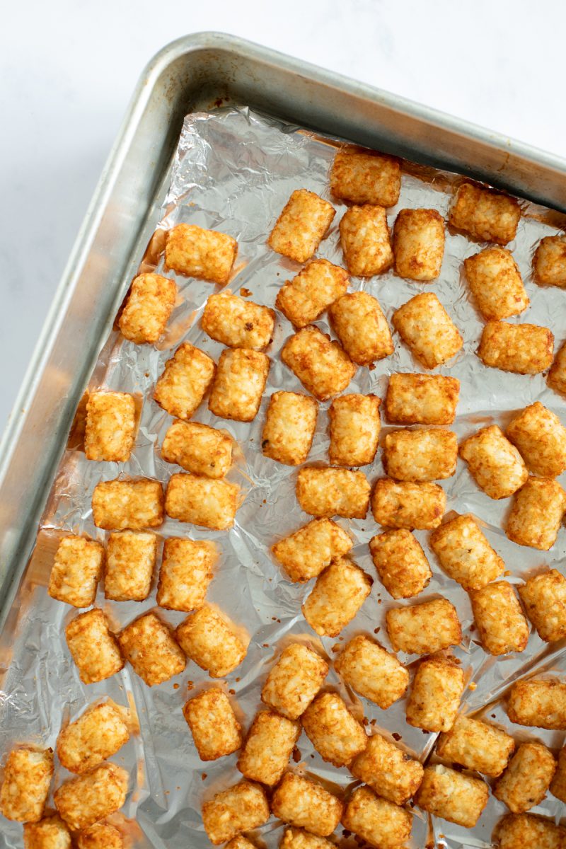 Cooked tater tots on a baking sheet.