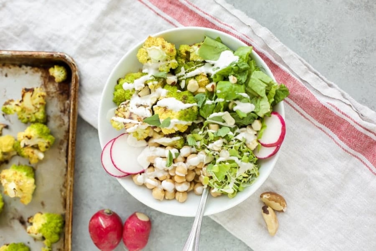 A bowl of cauliflower salad with chickpeas and radishes.