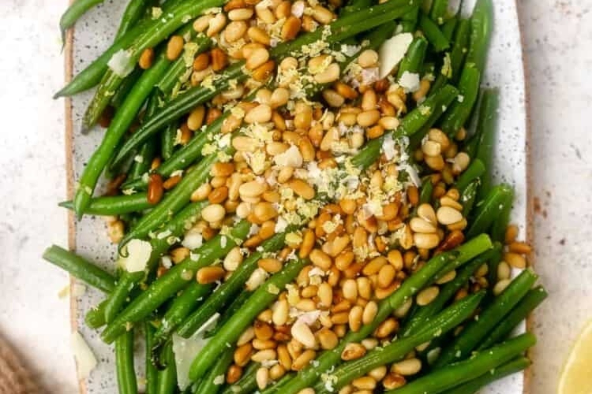 Green beans with pine nuts on a white plate.