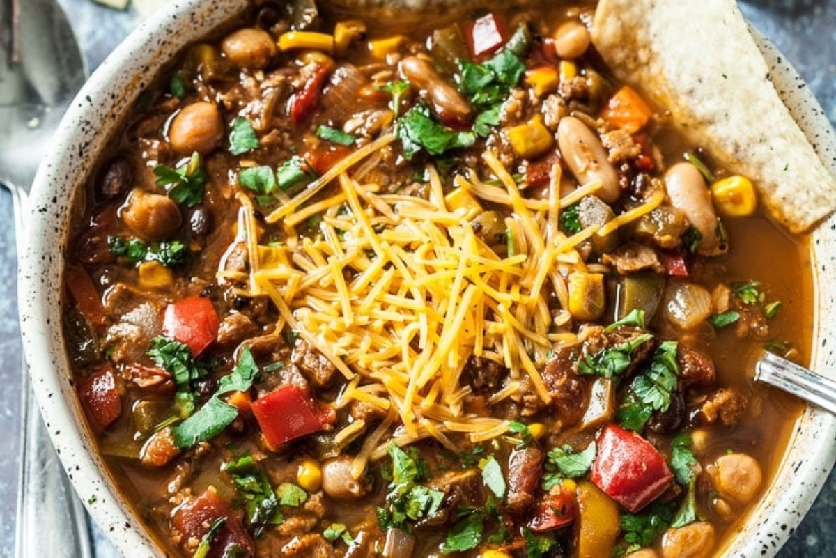 Mexican chili in a bowl with tortillas and cheese.