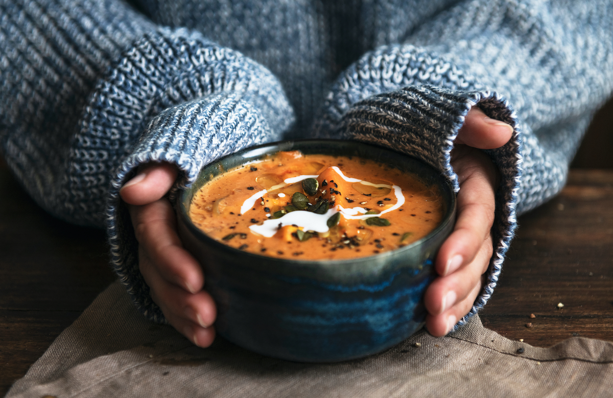 Female hands holding a bowl of pumpkin soup